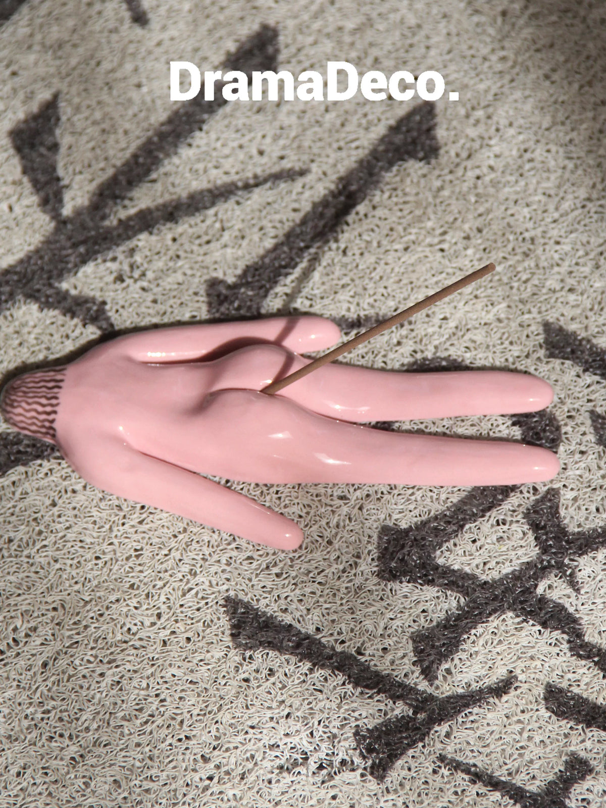 Pink ceramic incense holder with incense stick on textured mat