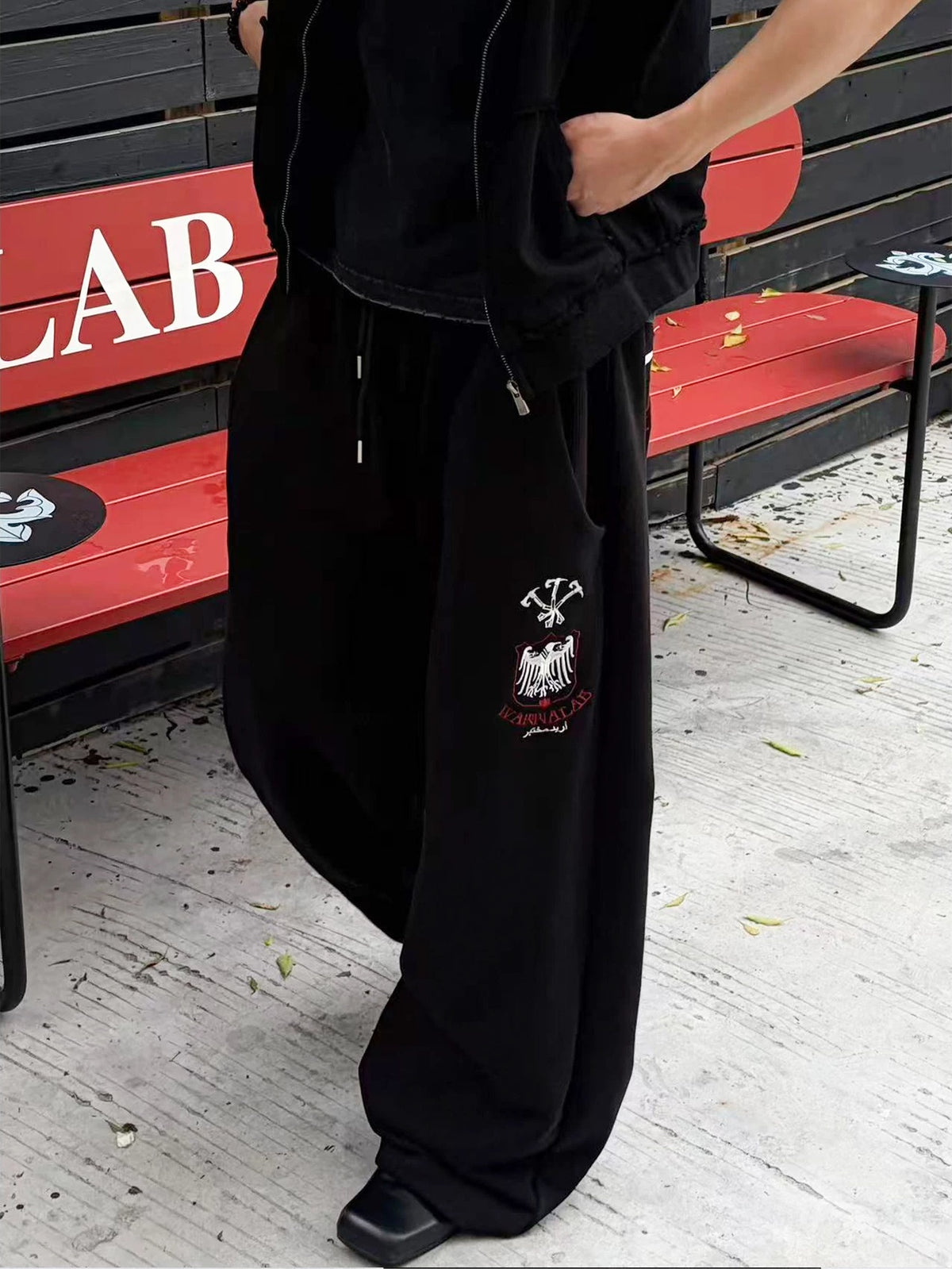 WANNA LAB Greyhound Flame Embroidered Cuffed Wide Sweatpants - Black front on model