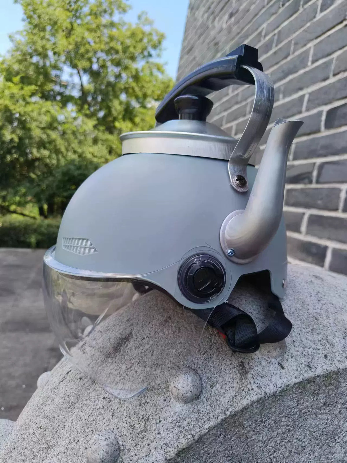 Gray kettle-shaped costume photo prop hat with clear visor outdoors
