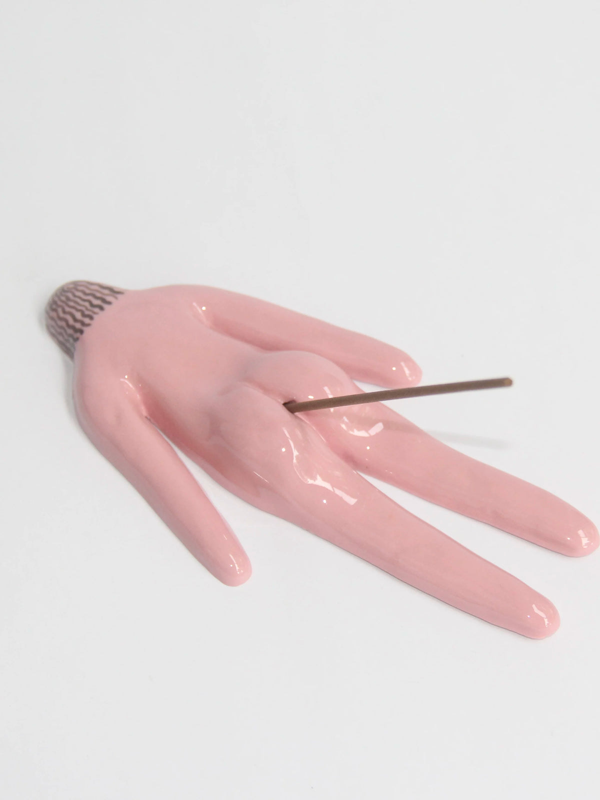Pink ceramic butt-shaped incense holder on a white background