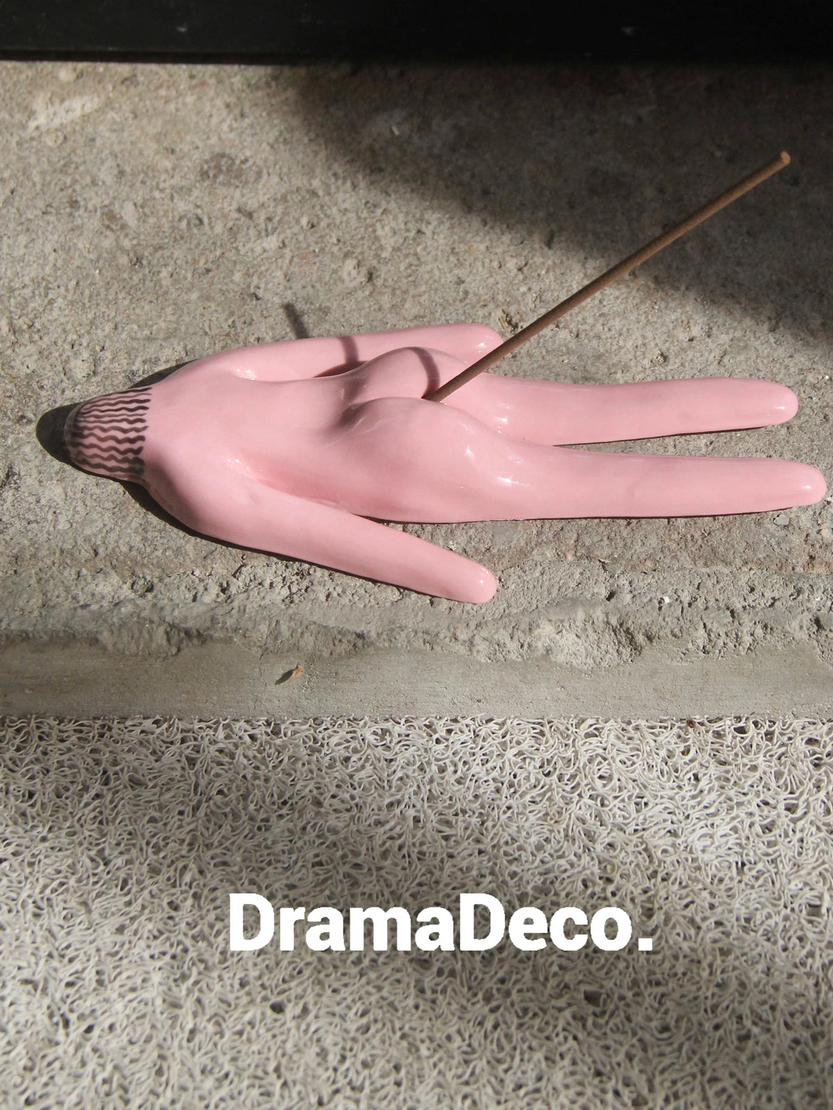 Pink ceramic incense holder with incense stick on concrete