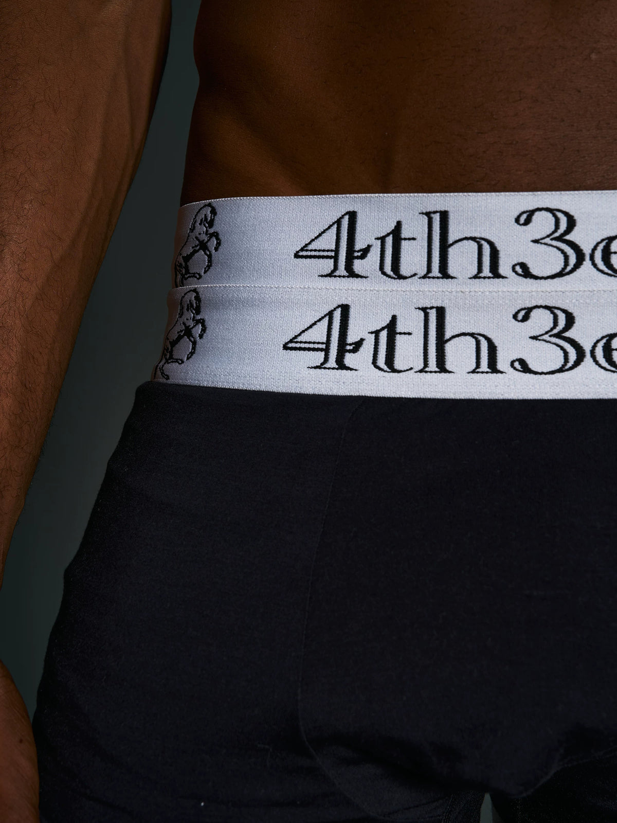 Close-up of horse-embroidered double waistband on black boxer briefs