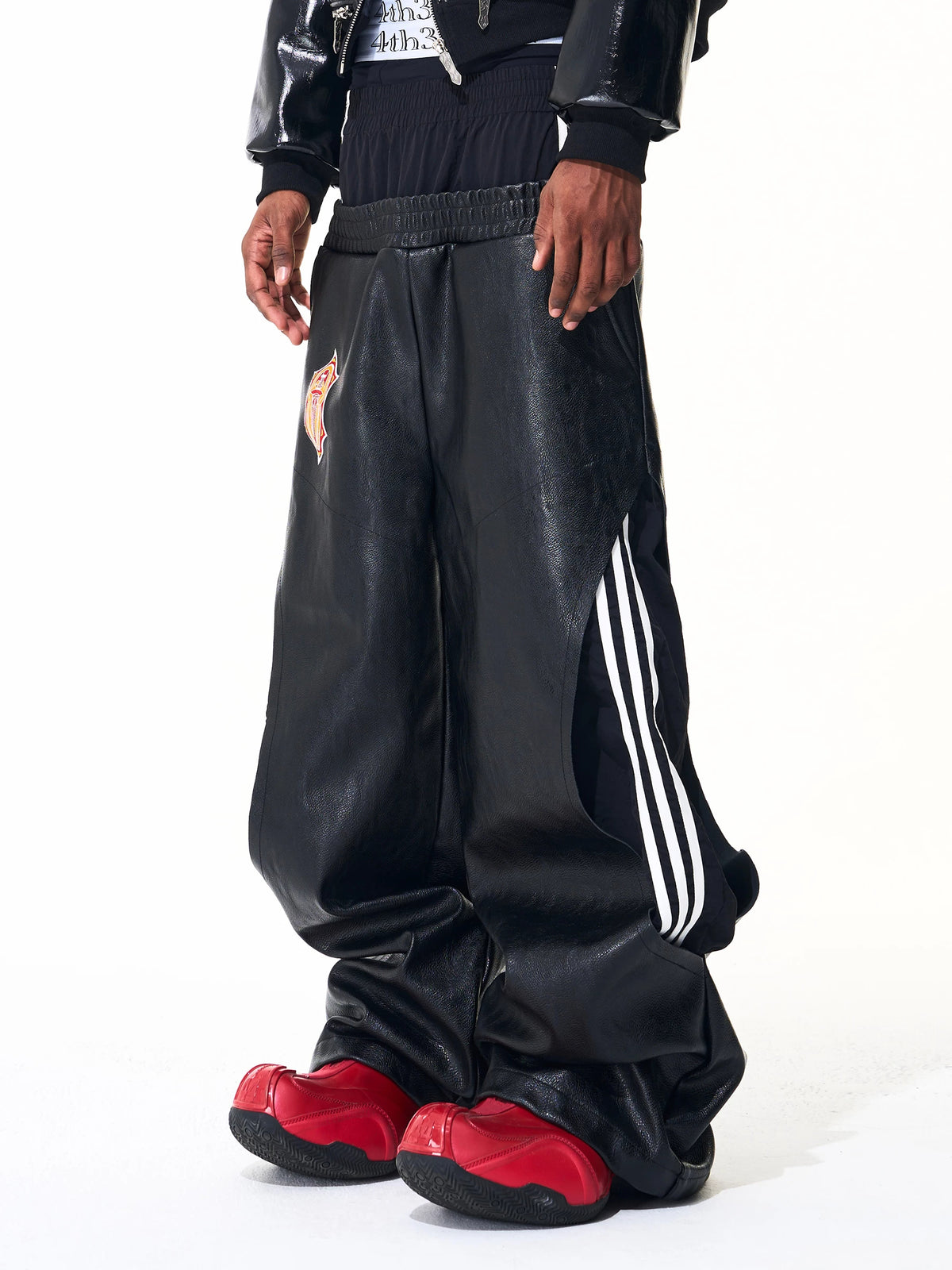 Front angled view of black leather-look double-waistband wide-leg pants with striped side panels