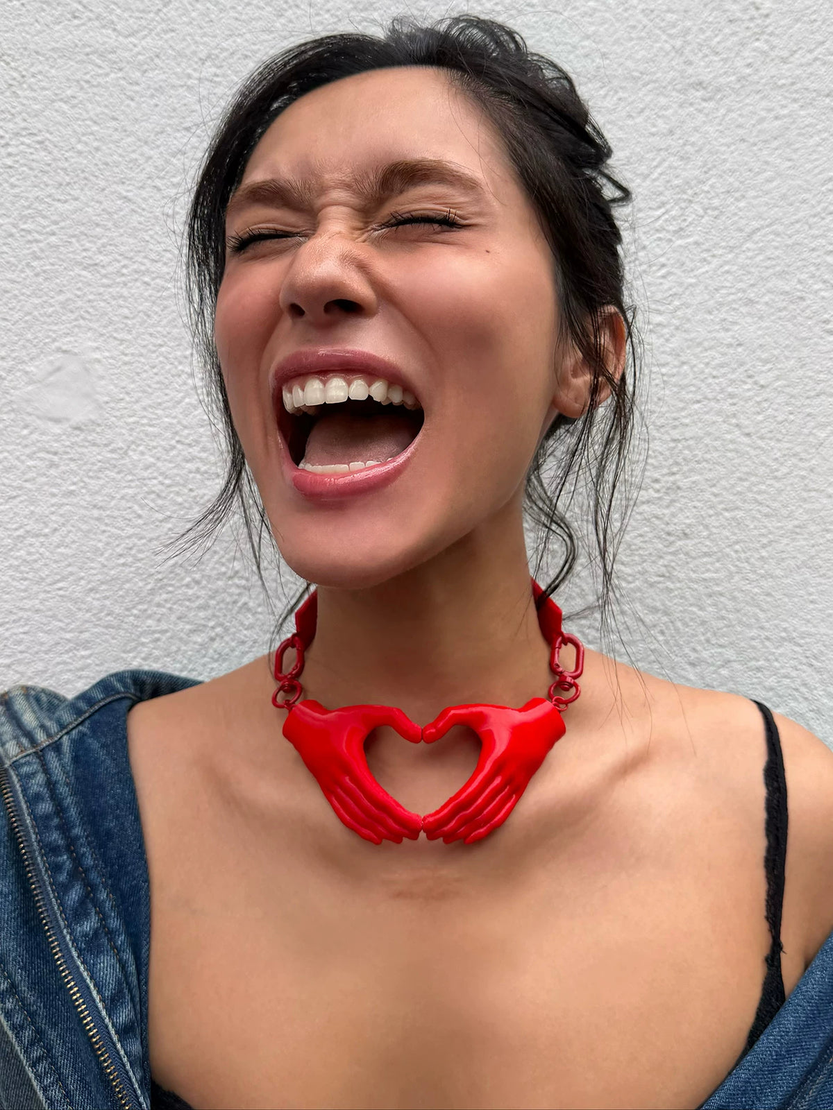 Red magnetic heart hands necklace on model, front view
