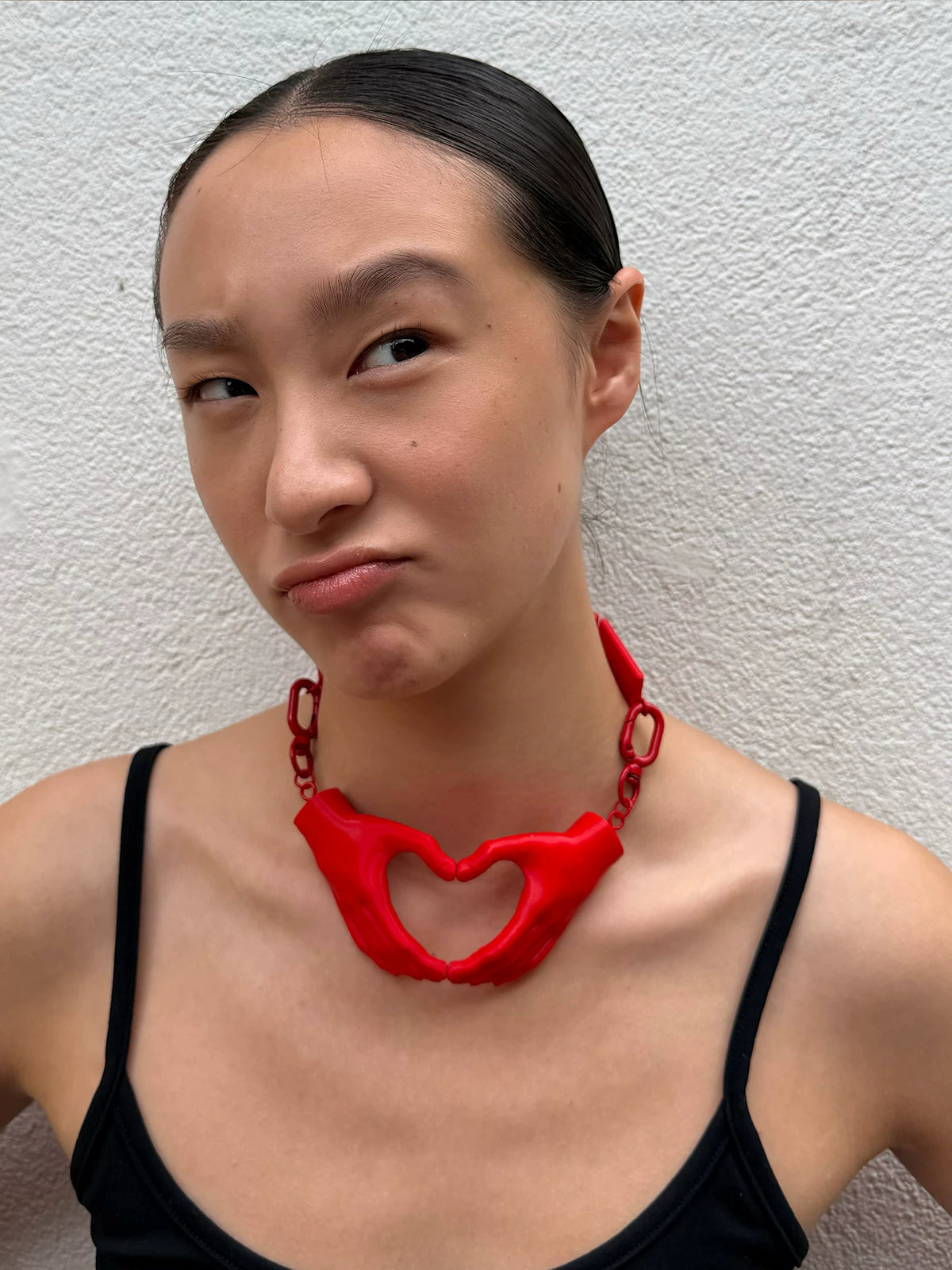 Red heart hands necklace styled with black top, front view