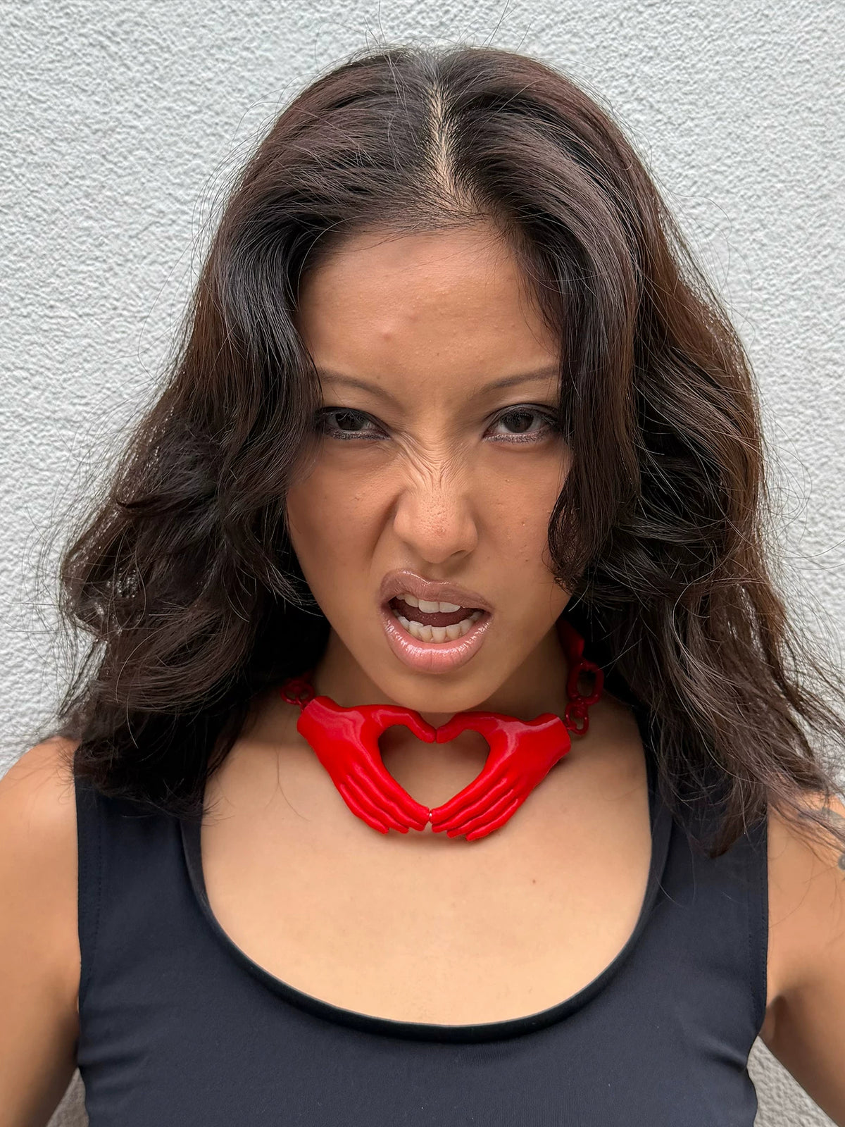 Red heart hands necklace on model with black top
