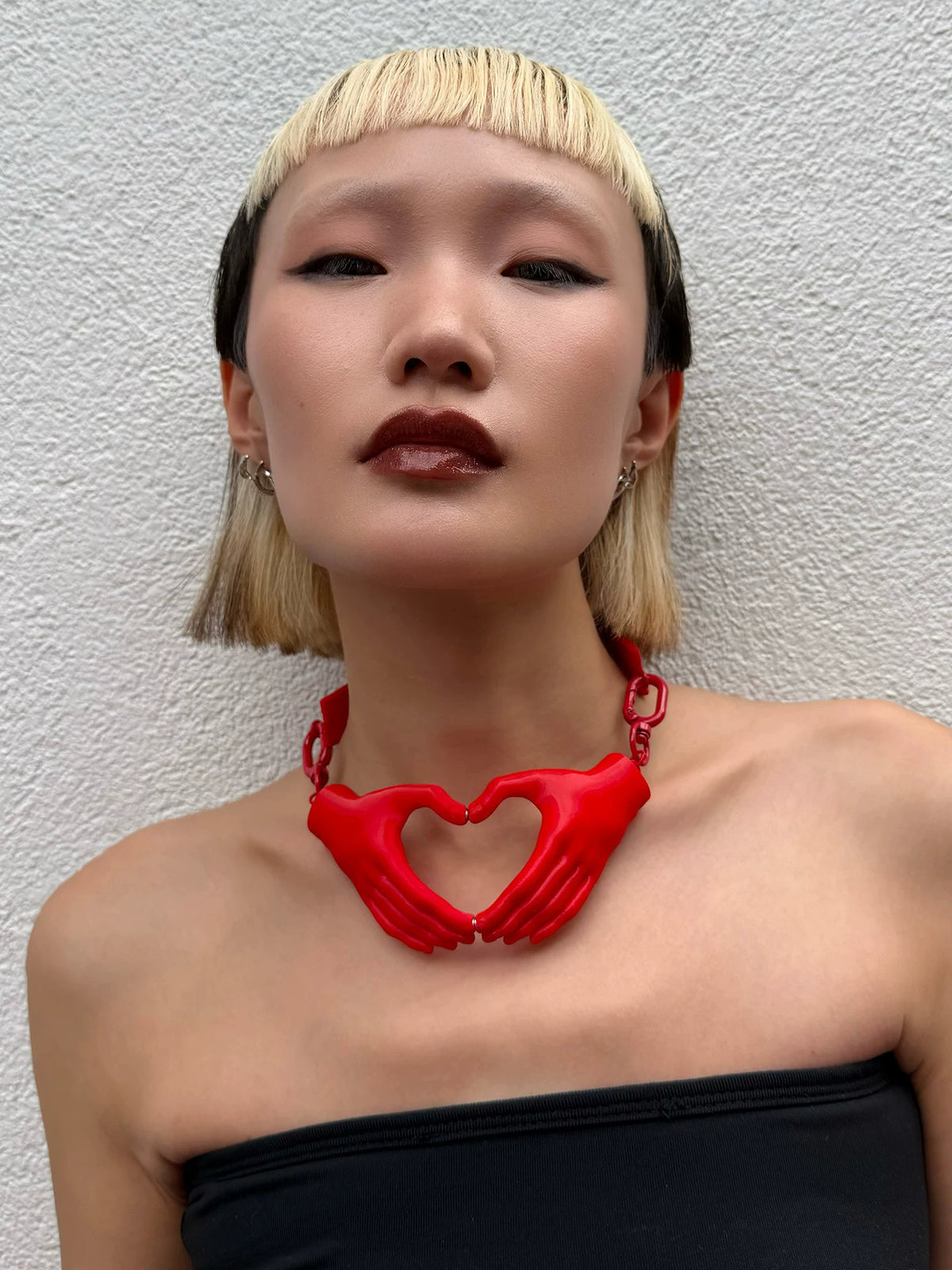 Red heart hands necklace worn with black strapless top